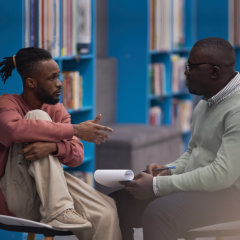 Side view portrait of black student talking to mental health therapist or guidance counselor in college library