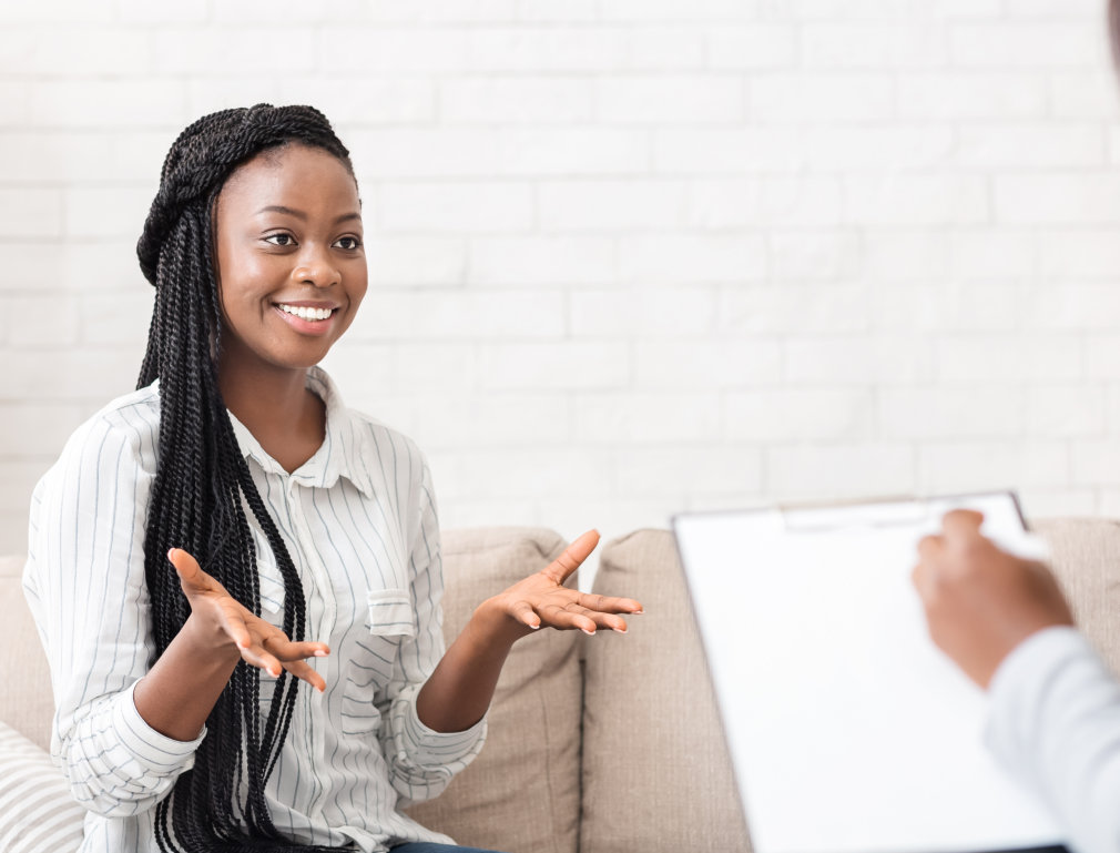 Successful therapy. Happy black female patient talking to psychologist at her office, expressing gratitude