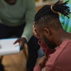 Troubled black man crying in support group circle and sharing story with therapist, copy space