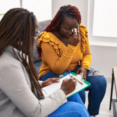 African american women psychologist and patient having mental therapy sitting on sofa at psychology clinic 