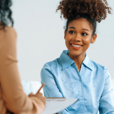 Happy patient and psychologist have mental health conversation in clinic with positive emotion while explaining crucial successful work and life to psychologist in home office