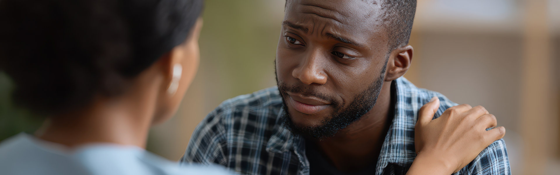 Compassionate black female therapist comforting distressed young man in clinic Emotional support theme