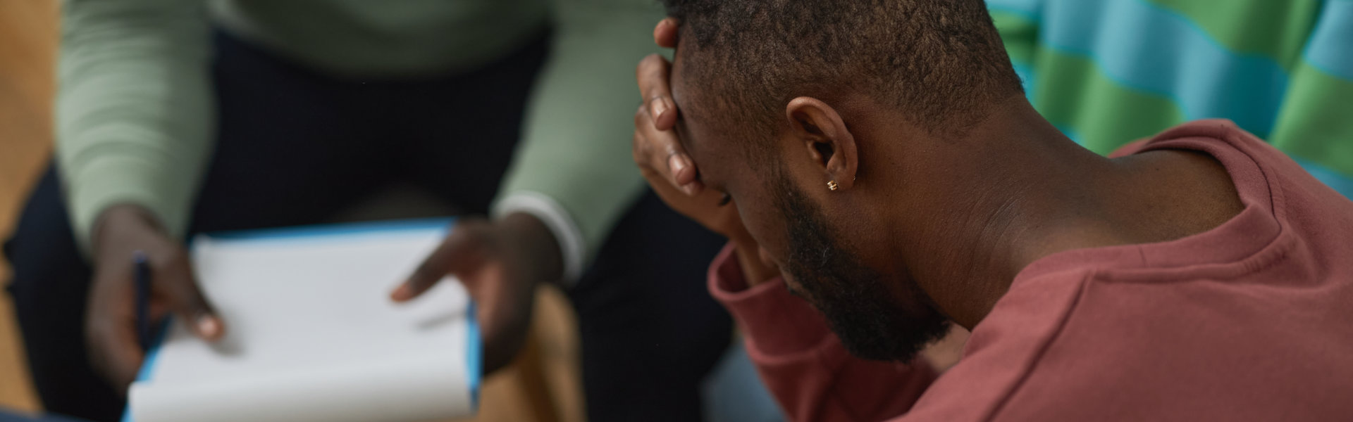 Troubled black man crying in support group circle and sharing story with therapist, copy space
