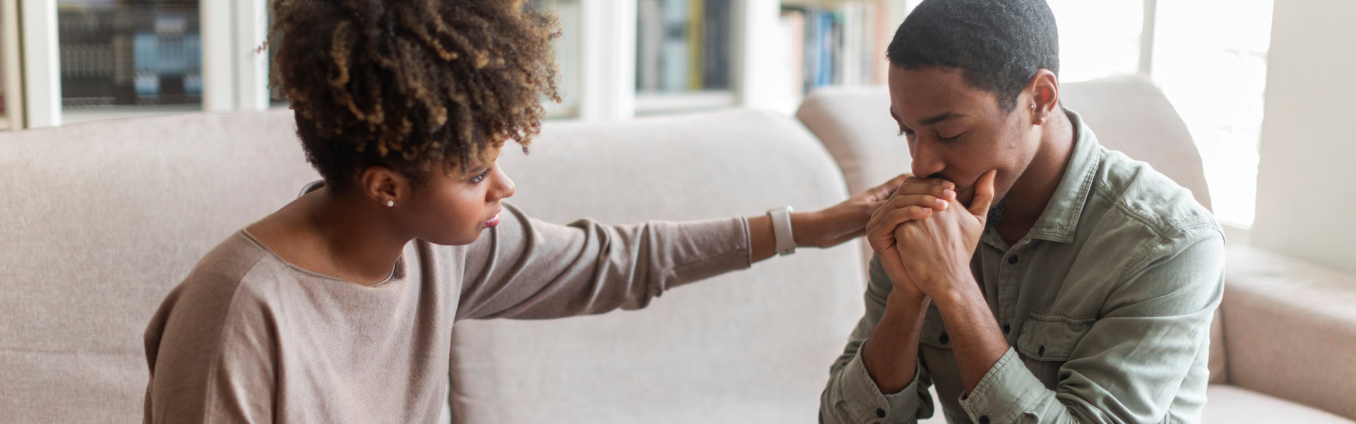Young african woman psychologist consoling upset man